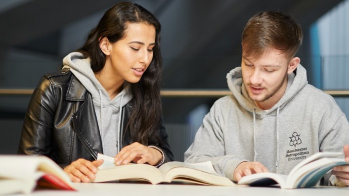 Two undergraduate students looking through textbooks
